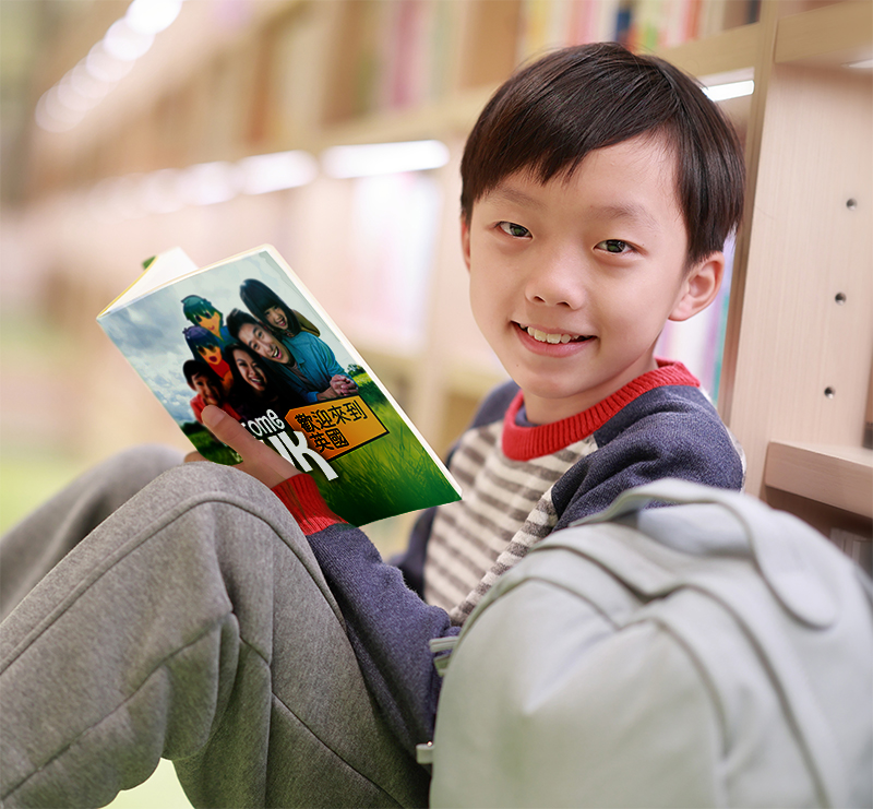 Young boy reading The Welcome to the UK book